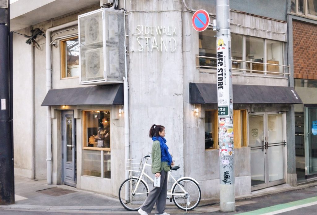 城市街角的日常街景,一位行人牽著腳踏車行走在街道上,用於首頁中段作為視覺留白與節奏轉換的背景畫面。